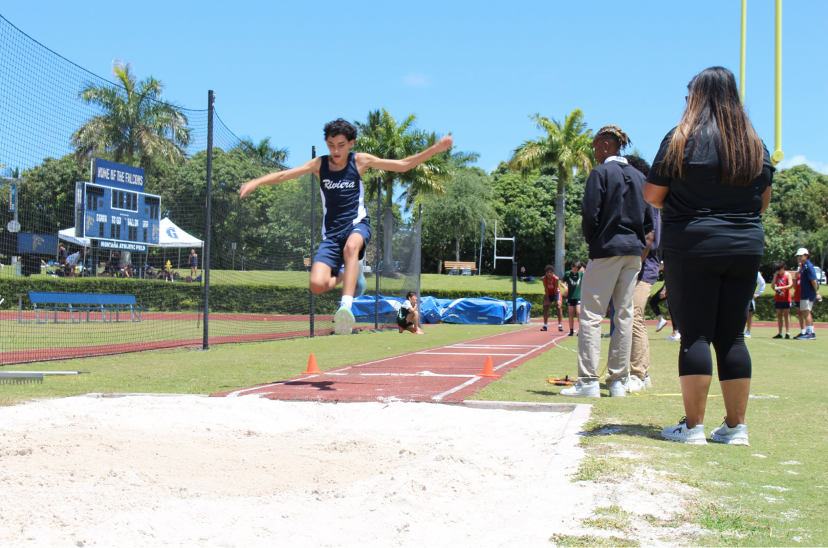 Sebastian Parra flying in the air in the jump event while being cheered on by Coach Rizo. 
