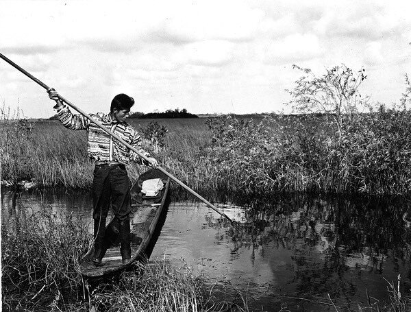 Miccosukee gigging in the Everglades in a dug-out canoe. 
