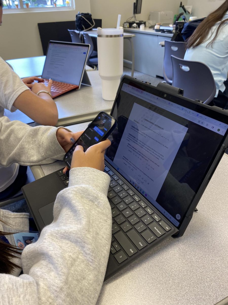 A student looks at their phone in class. Students say allowing phones during lunch would reduce the temptation to check them during lessons.