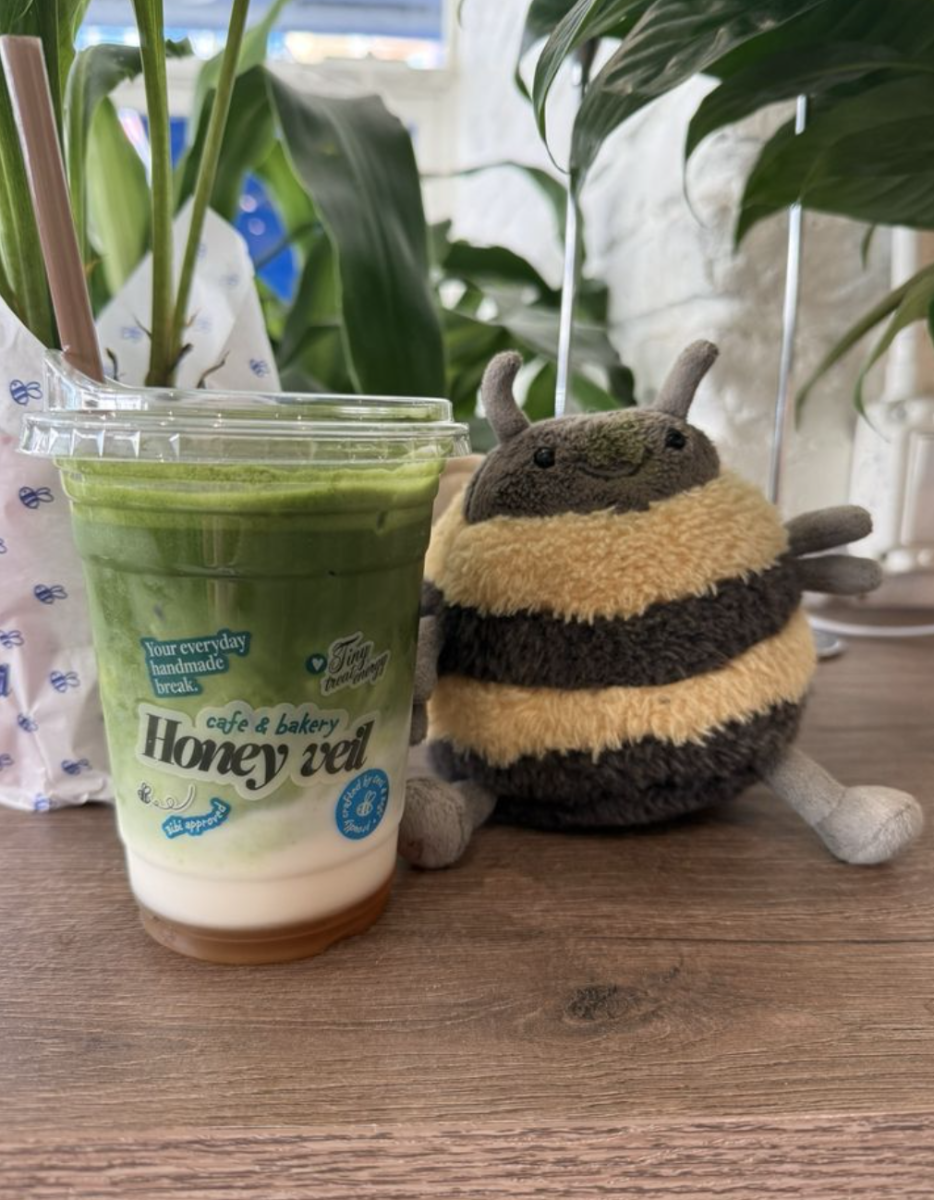 Fan favorite Banana Bread Matcha next to the stores mascot, a honey bee. This is at the South Miami location of Honey Veil 